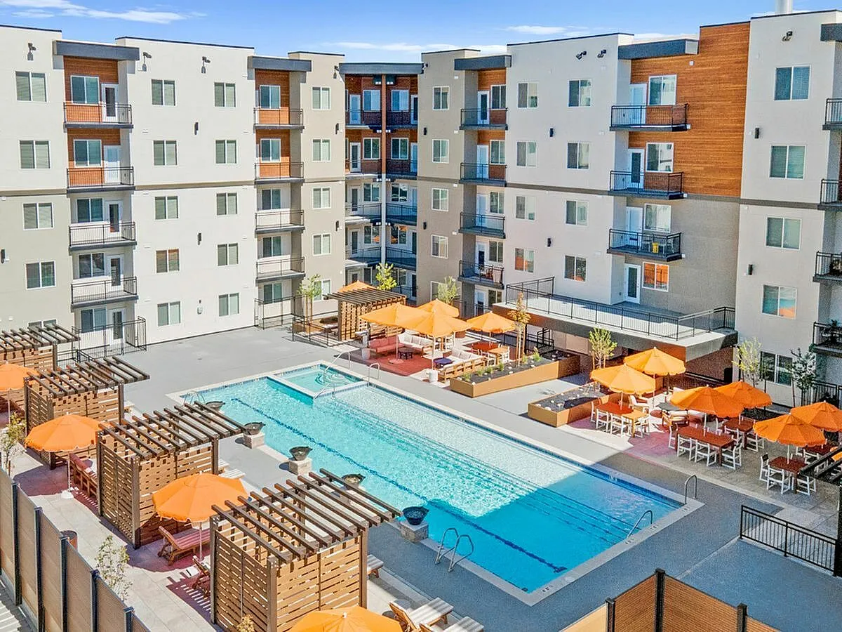Vibrant apartment courtyard featuring a sparkling swimming pool, chic cabanas, and inviting orange umbrellas, perfect for relaxation and social gatherings  at Current Apartments in Murray Utah