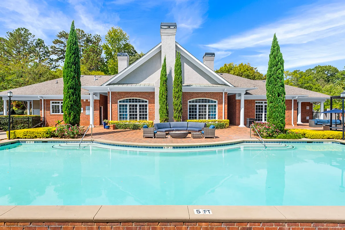 Inviting resort-style pool area with elegant brick architecture and lush greenery, perfect for relaxation and leisure  Retreat at Peachtree City Apartments