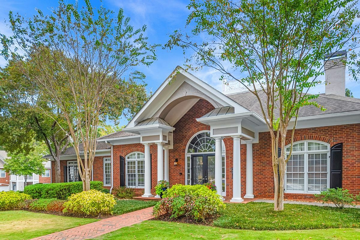 Charming brick-front apartment with grand entrance, classic white columns, and lush landscaping at Retreat at Peachtree City Apartments