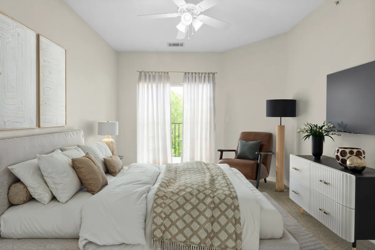 Elegant bedroom with a cozy queen-sized bed, stylish decor, and abundant natural light through sheer curtains, creating a serene retreat at Cottonwood Reserve Apartments in Charlotte NC