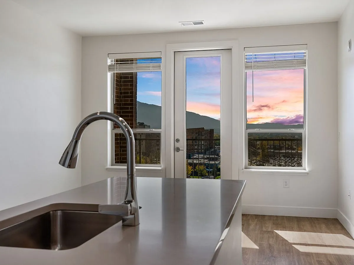 Modern kitchen space with sleek faucet and counter, offering stunning sunset views through large windows  at The Richmond Apartments in Salt Lake City, UT.