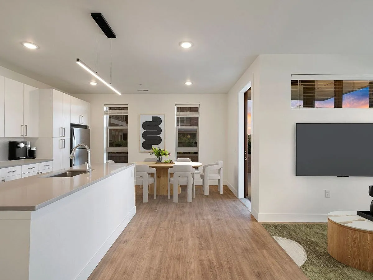 Modern open-concept kitchen and dining area with sleek white cabinetry, elegant lighting, and inviting natural light at The Richmond Apartments in Millcreek UT