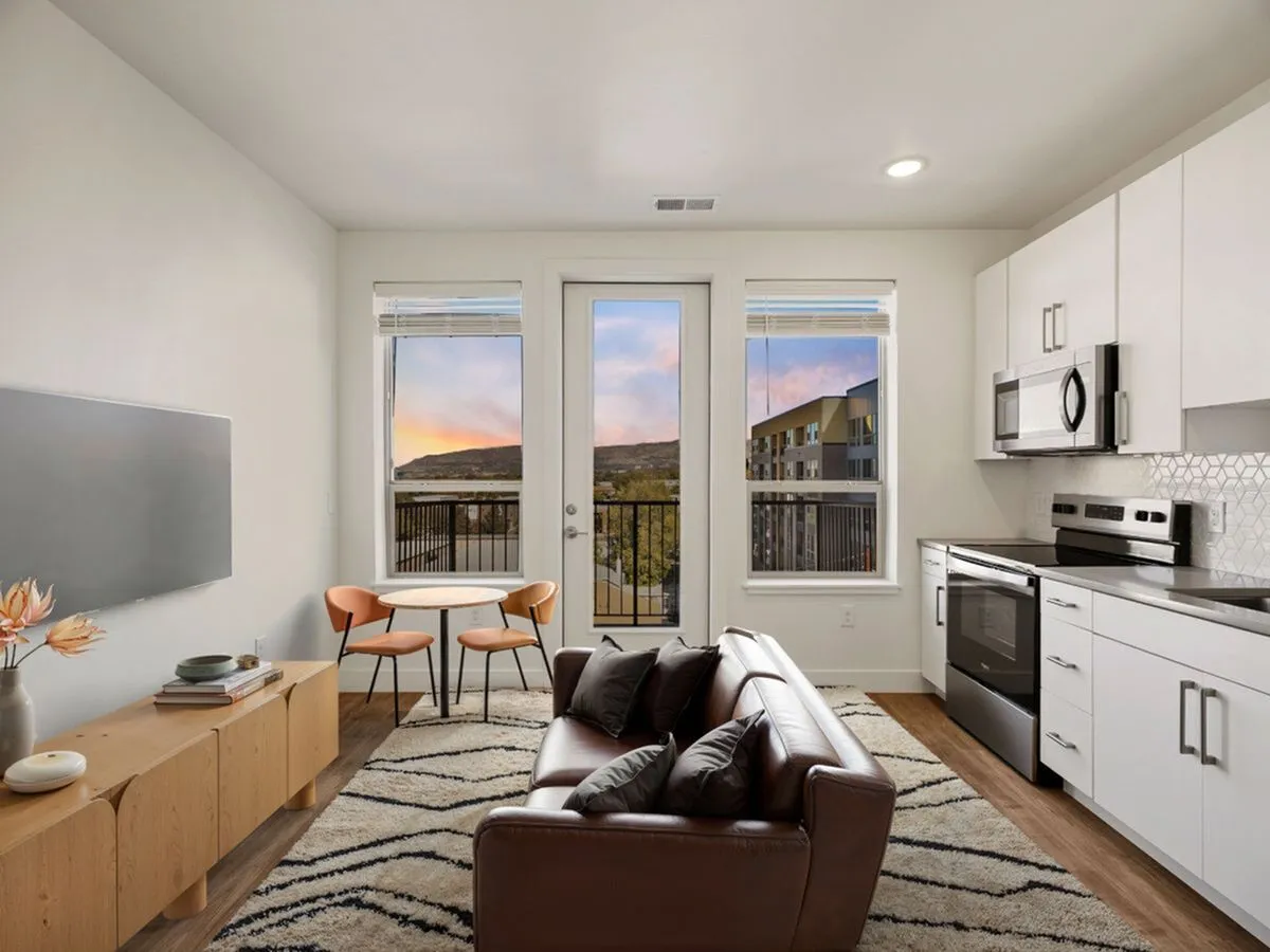 Chic modern apartment living space with stylish furniture, stainless steel appliances, and large windows showcasing a stunning sunset view at The Richmond Apartments in SLC
