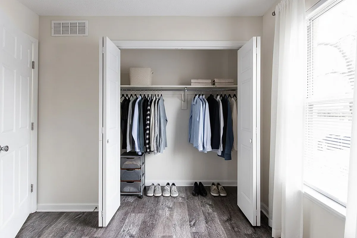 Chic and spacious closet at Crown Pointe Apartments with organized clothing, shoes, and elegant wood flooring.