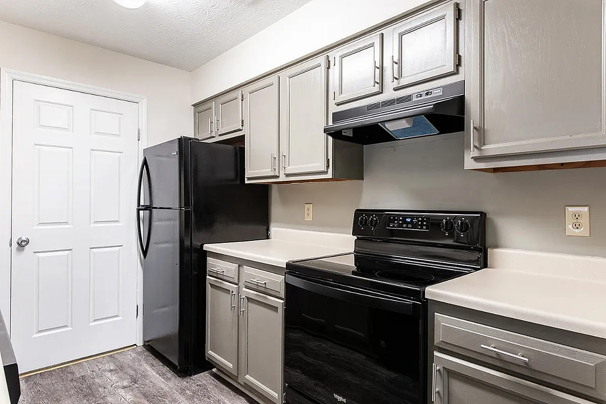 Modern kitchen at Crown Pointe Apartments with sleek black appliances and stylish gray cabinetry, offering a contemporary and functional cooking space.