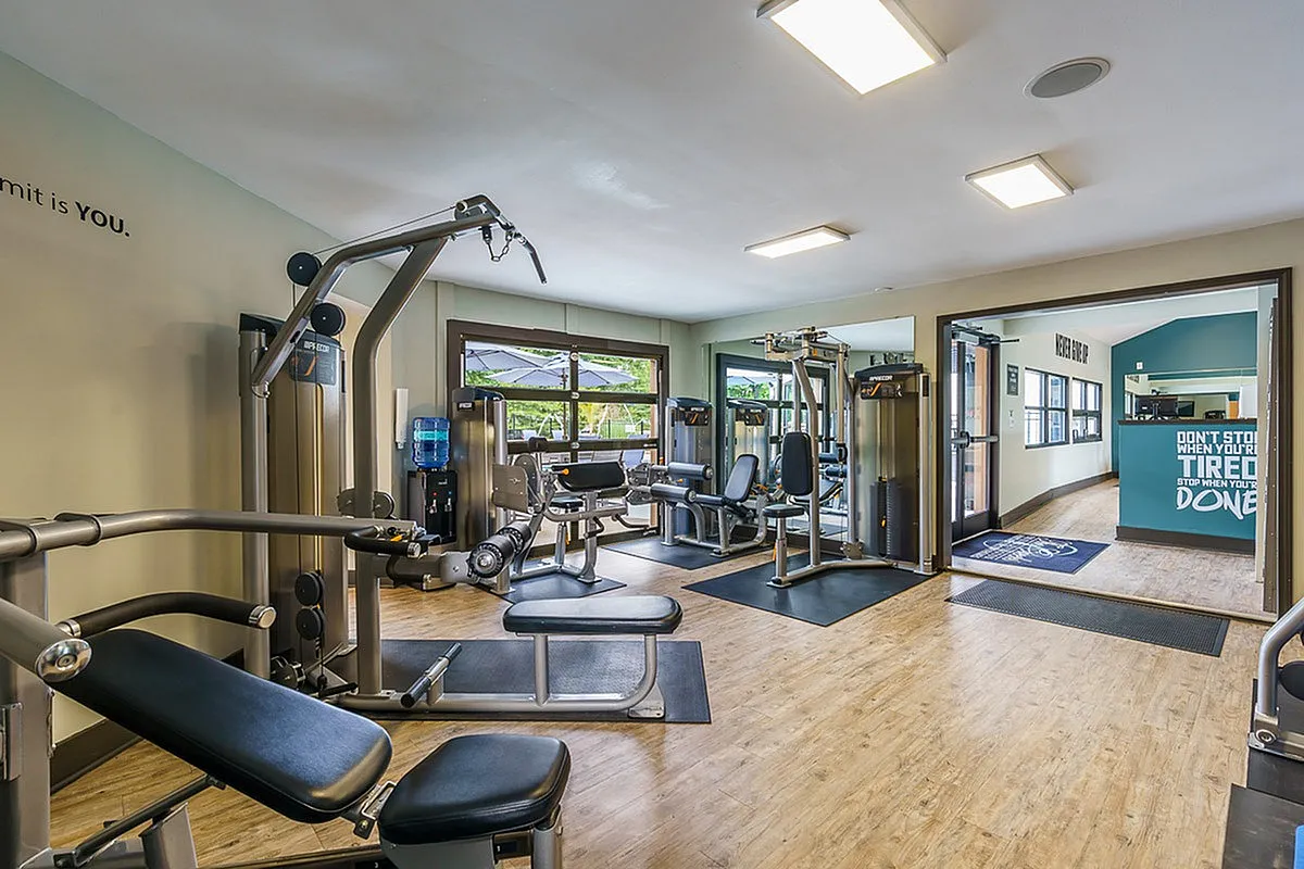 Modern fitness center at The Creeks on Kirklevington Apartments with state-of-the-art gym equipment, bright windows, and motivational decor.