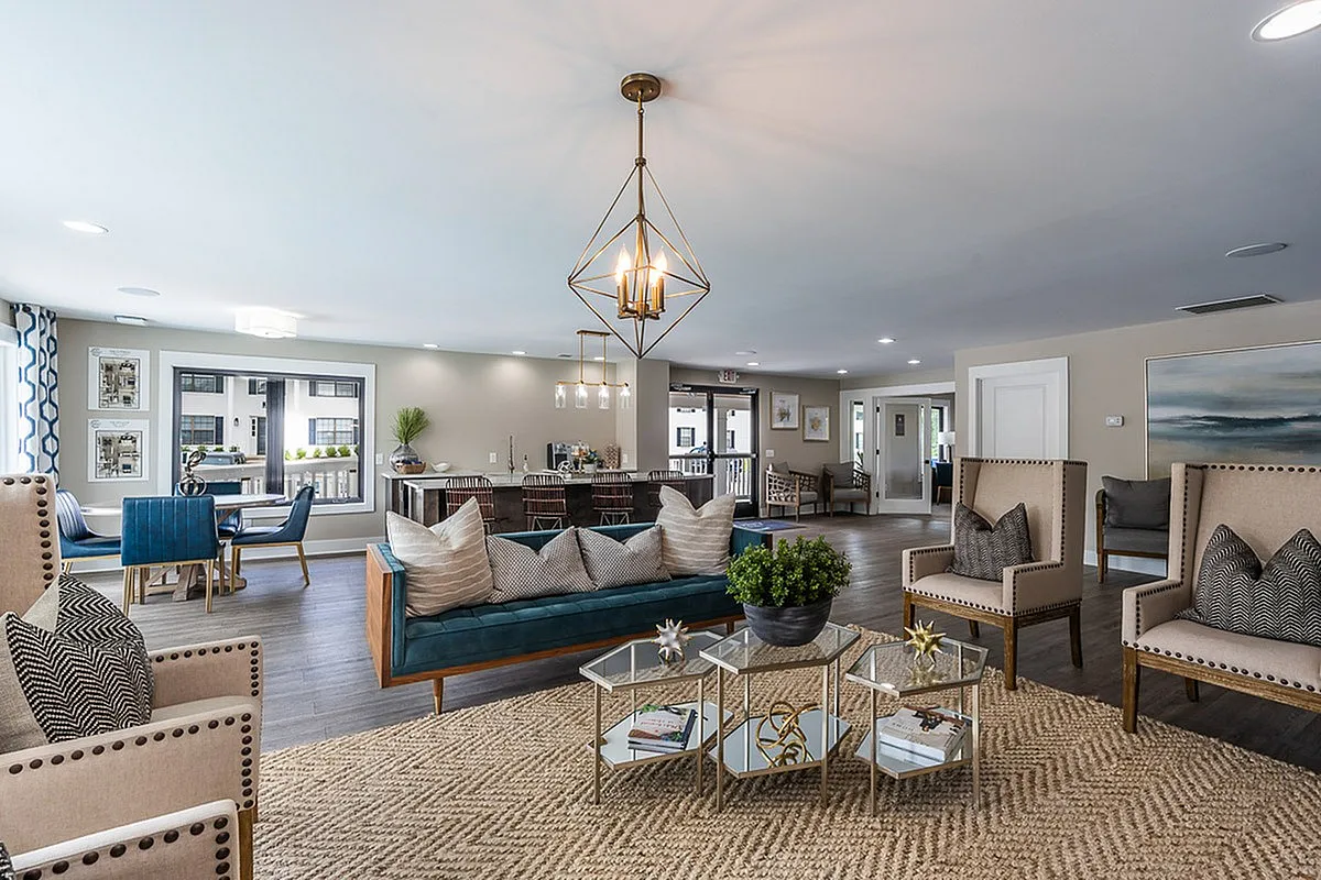 Chic and spacious clubroom at The Colony at the Oaks Apartments with elegant chandelier, plush seating, and modern decor, perfect for relaxation and entertaining.