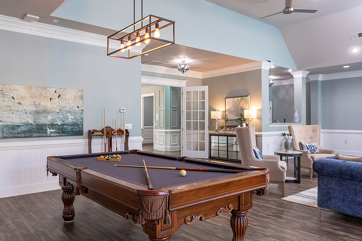Elegant and inviting clubroom at The Stratford at Hillcrest Towne Center Apartments featuring a stylish billiard table, modern lighting, and comfortable seating, perfect for entertaining and relaxation.