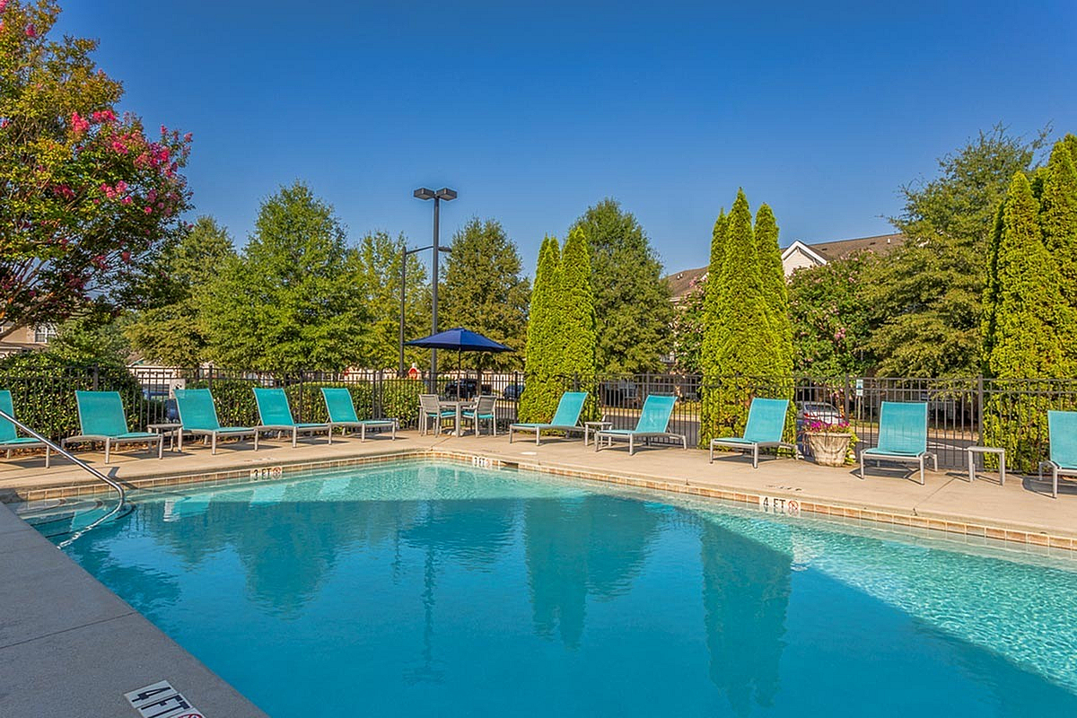 Inviting outdoor pool with vibrant lounge chairs and lush greenery, perfect for relaxation and entertaining at The Stratford at Hillcrest Towne Center Apartments.