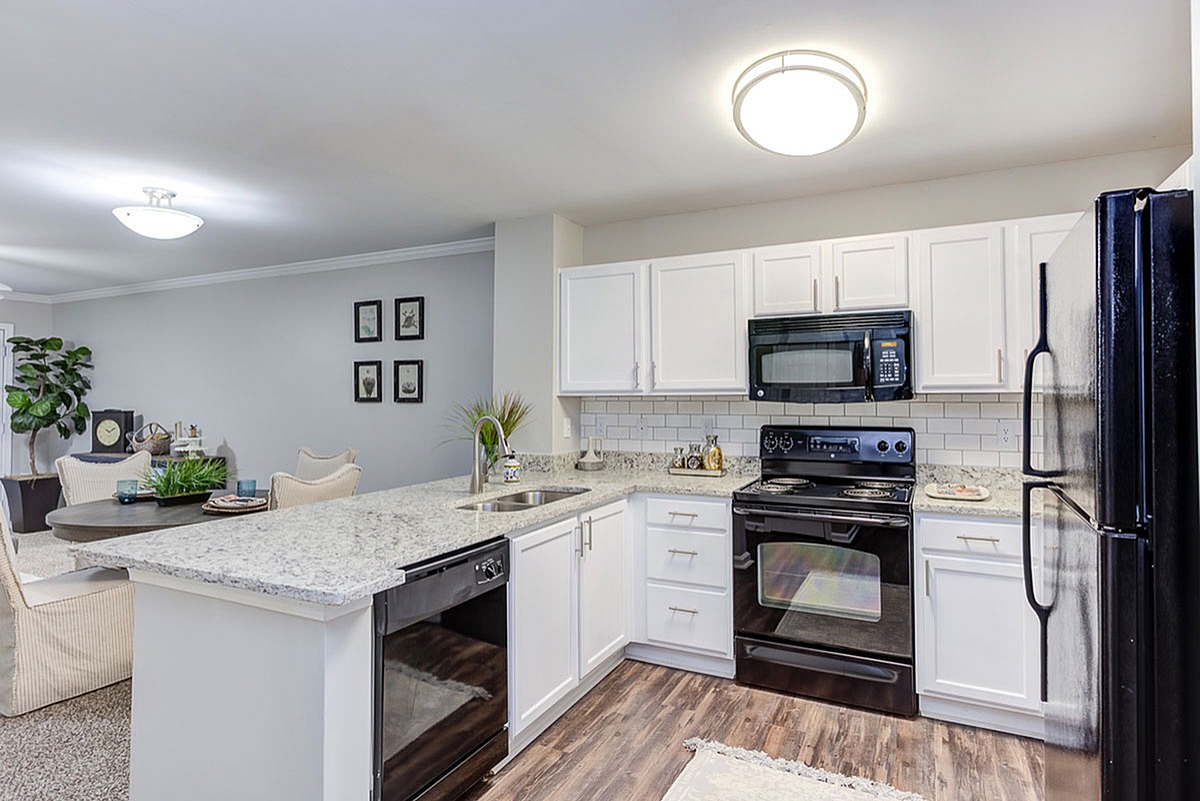 Chic open-concept kitchen and dining area with elegant granite countertops and modern appliances, creating a sophisticated ambiance at The Stratford at Hillcrest Towne Center Apartments.