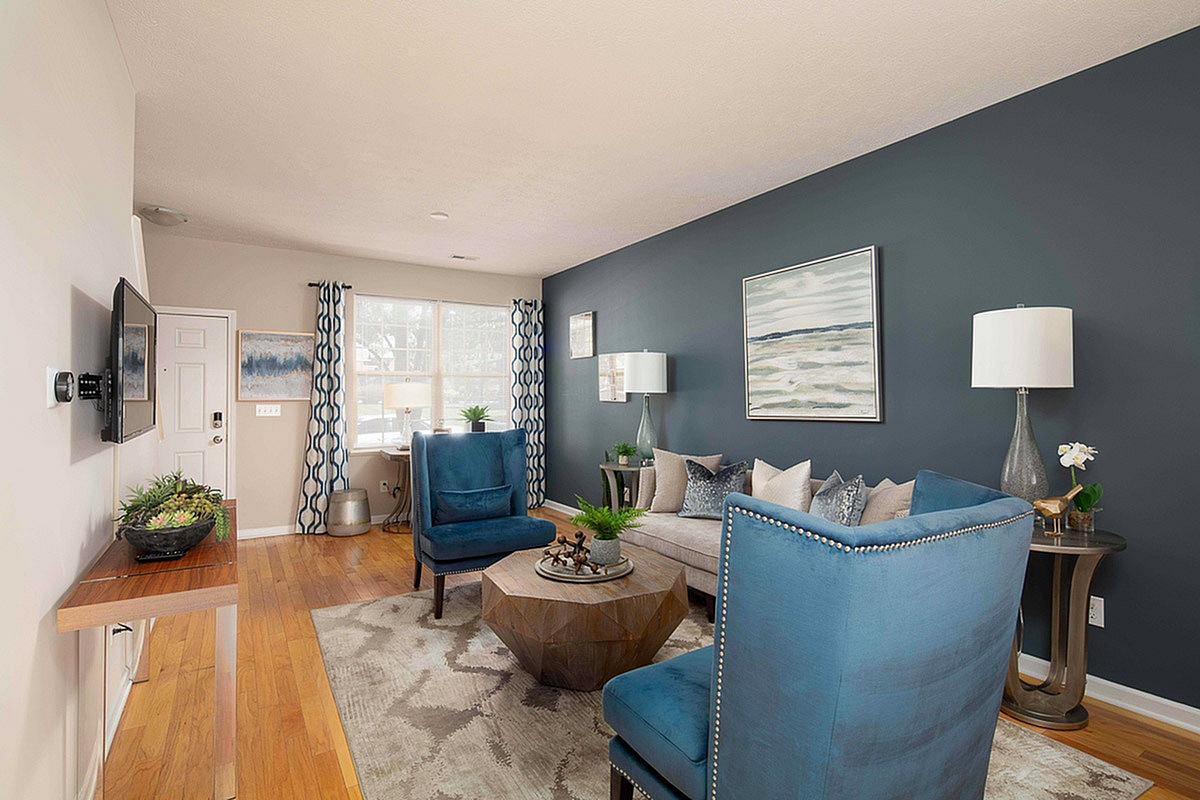 Elegant living room at The Mill at Georgetown Apartments with stylish blue armchairs, modern decor, and abundant natural light.