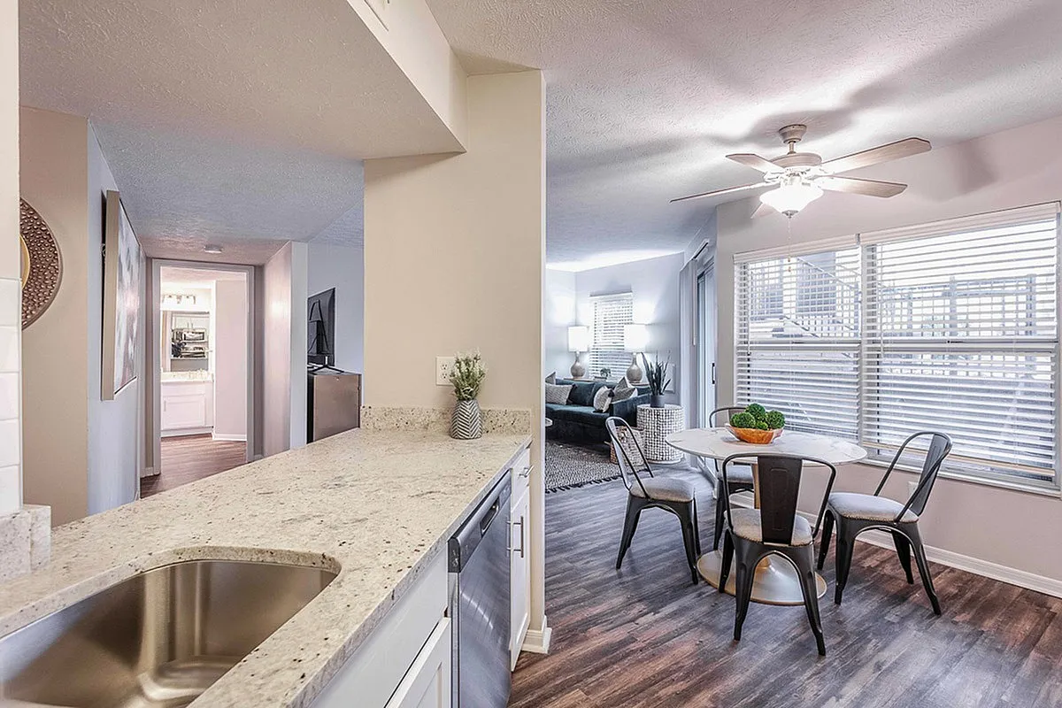 Sleek open-concept kitchen and dining area with elegant finishes, seamlessly connecting to a cozy, well-lit living room at The Retreat at Stillmeadow Apartments.