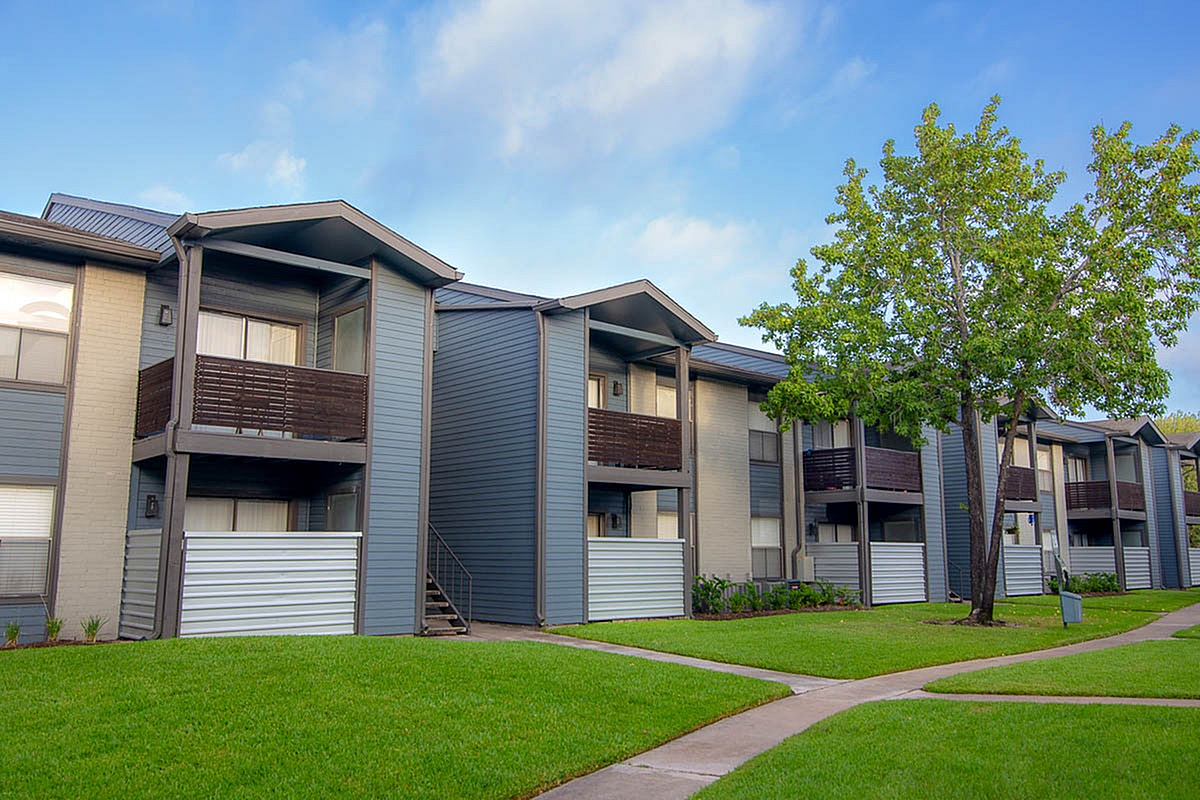 Beautiful modern apartment complex with private balconies and lush green lawns, under a clear blue sky at Steepleway Downs Apartments.