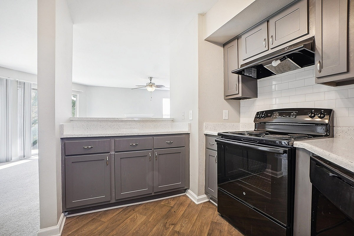 Modern kitchen at Park at Midtown Apartments with elegant gray cabinetry, black appliances, and open layout perfect for social gatherings.
