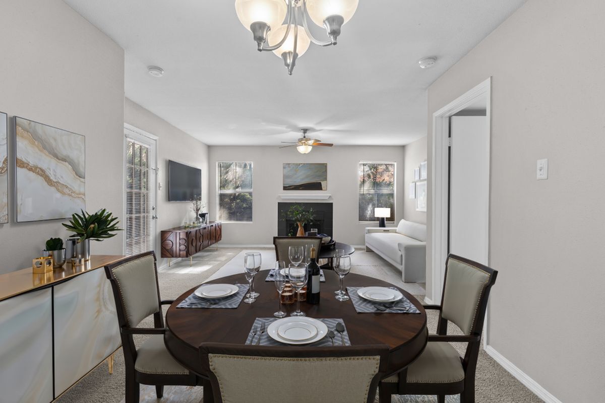 Elegant open-plan dining and living area featuring a beautifully set dining table, large windows for natural light, and a cozy fireplace, creating a warm and inviting ambiance at Park at Midtown Apartments