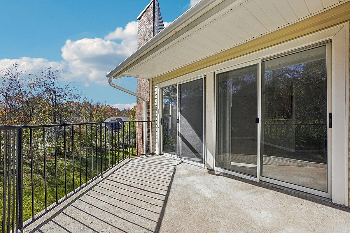 Sunny balcony with sliding glass doors offering a serene view of lush greenery, perfect for relaxation and enjoying the outdoors at Park at Midtown Apartments.