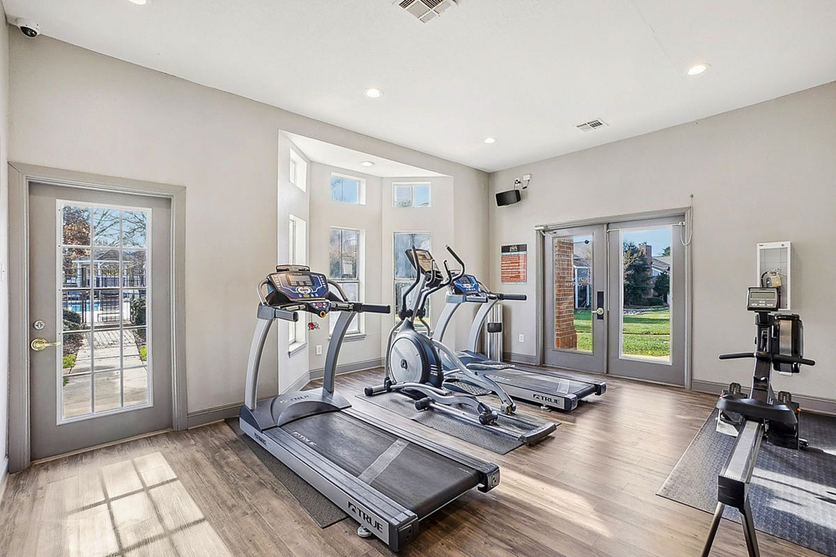 Bright and inviting gym at Park at Midtown Apartments with modern equipment, featuring large windows with scenic outdoor views.
