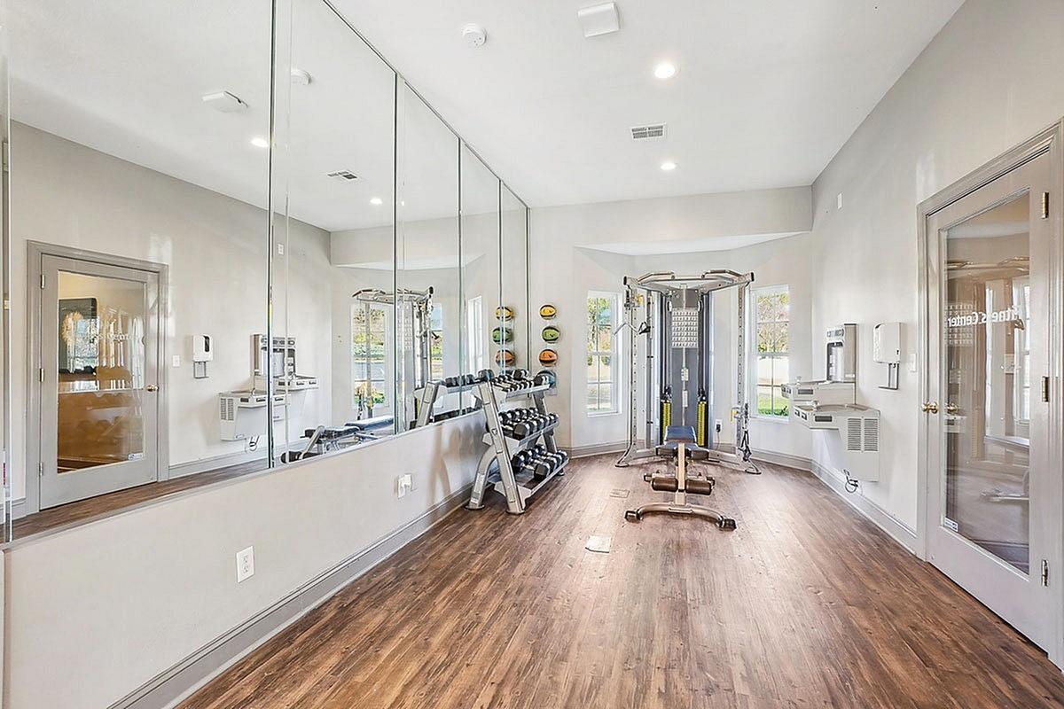 Bright and modern fitness center at Park at Midtown Apartments with mirrored walls, state-of-the-art exercise equipment, and sleek wooden flooring.