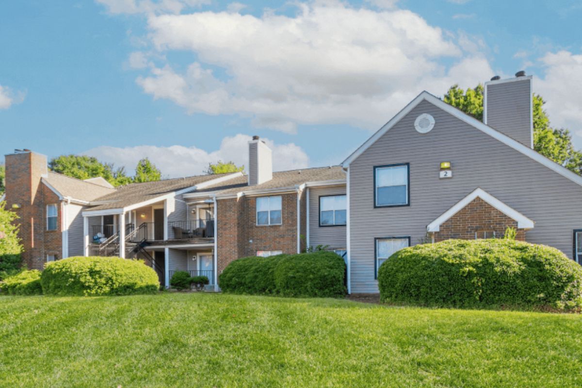 Charming apartment complex with brick and vinyl exteriors, lush green lawns, and spacious balconies, perfect for comfortable living at Park at Midtown Apartments