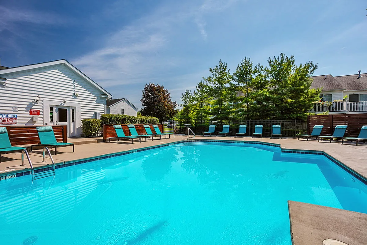 Inviting outdoor pool area at Alkire Glen Apartments in Columbus with sun loungers and tranquil surroundings, perfect for relaxation.