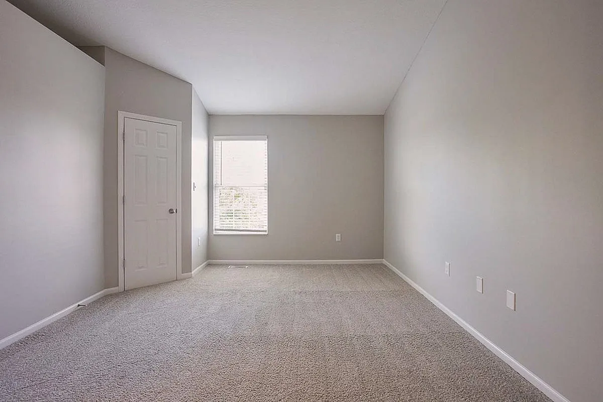 Bright and spacious room with plush carpeting and large window, perfect for a cozy bedroom setup at Alkire Glen Apartments.