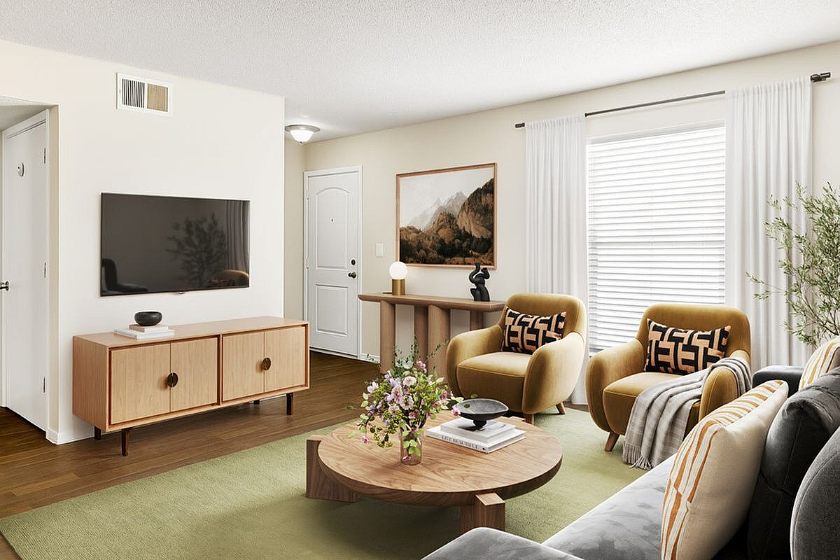 Elegant living room with stylish decor, featuring plush yellow armchairs, a modern wooden coffee table, and a sleek entertainment center with a flat-screen TV at Antero Apartments in Colorado Springs.