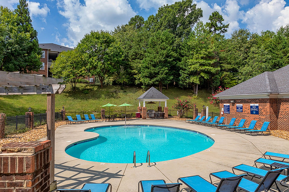 Inviting outdoor pool area at Morgan Ridge Apartments with lounging chairs, surrounded by lush greenery and a charming gazebo.