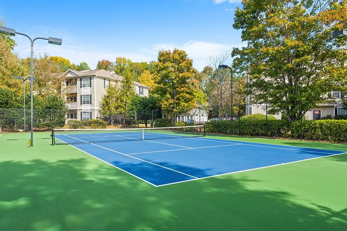 Inviting tennis court surrounded by lush greenery and modern apartment buildings, perfect for active living at Lake St James Apartments in Conyers GA.