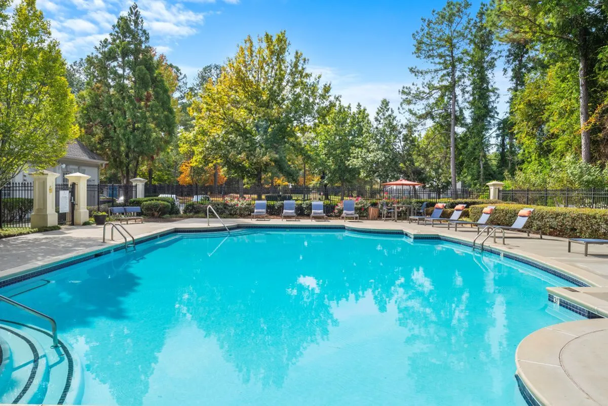 Inviting outdoor pool area surrounded by lush greenery and comfortable lounge chairs, perfect for relaxation and leisure at Lake St James Apartments in Conyers, GA.