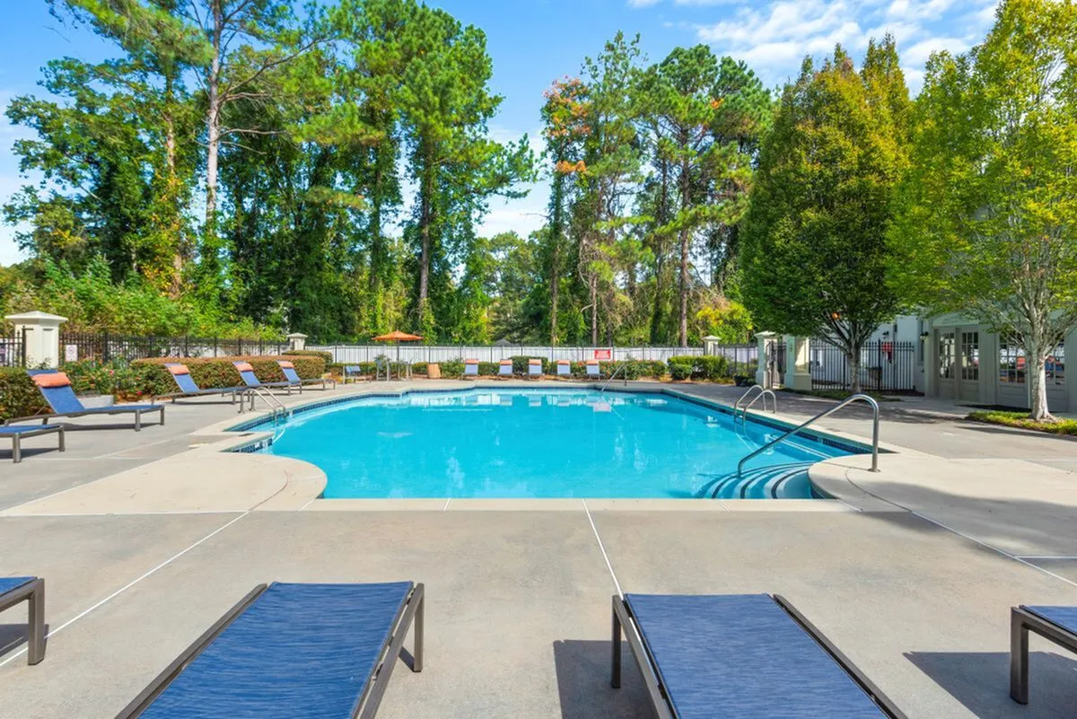 Inviting outdoor pool area with sun loungers, surrounded by lush greenery and a serene atmosphere at Lake St James Apartments