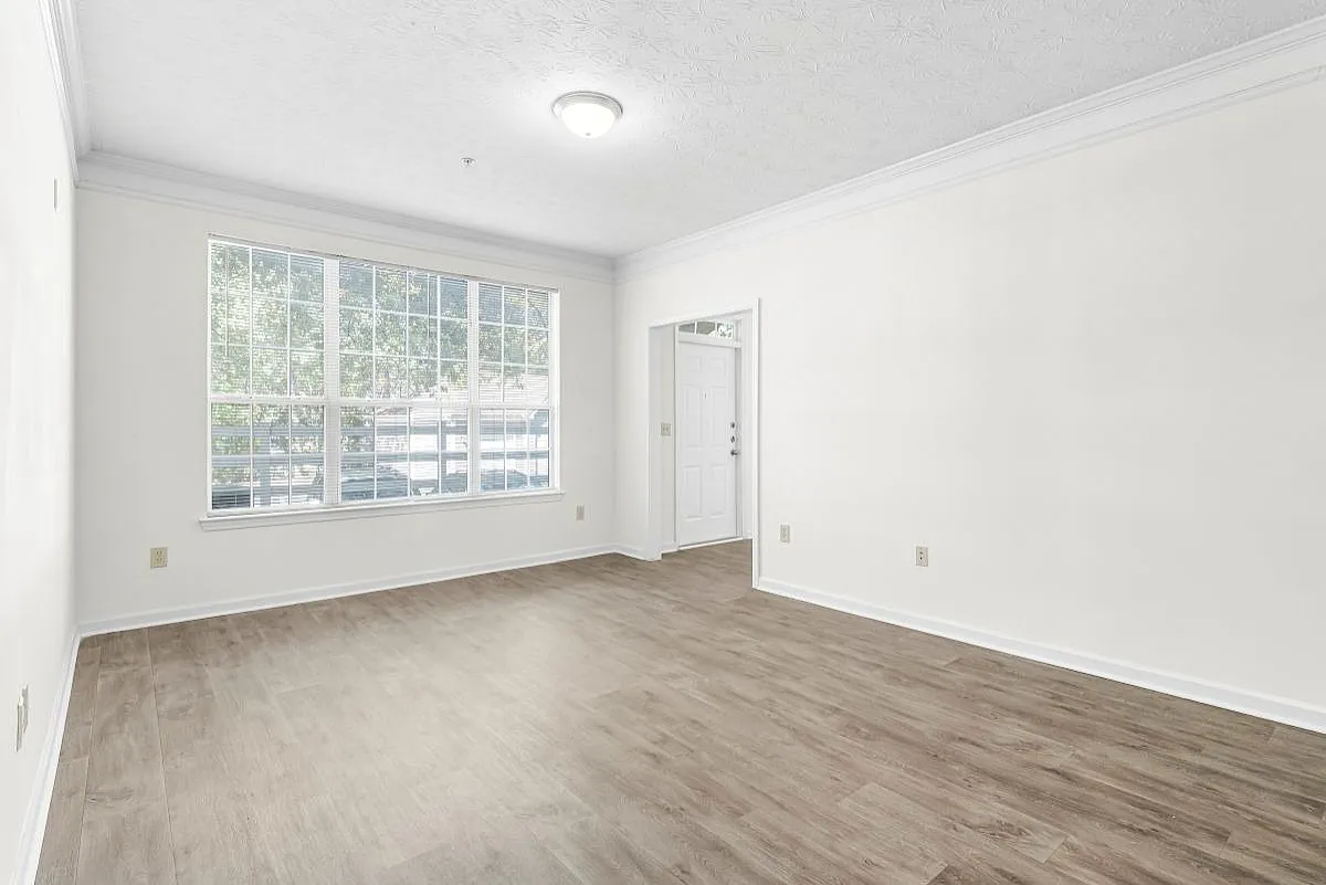 Bright and airy living room with large windows and elegant wood flooring, perfect for cozy gatherings and relaxation at Lake St James Apartments.