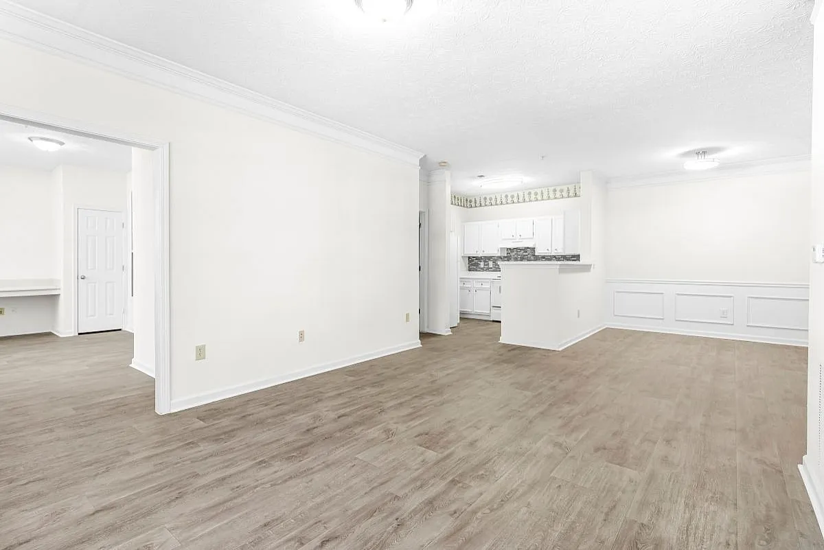 Bright and spacious living area with elegant hardwood flooring and an open kitchen design, perfect for modern living  at Lake St James Apartments.