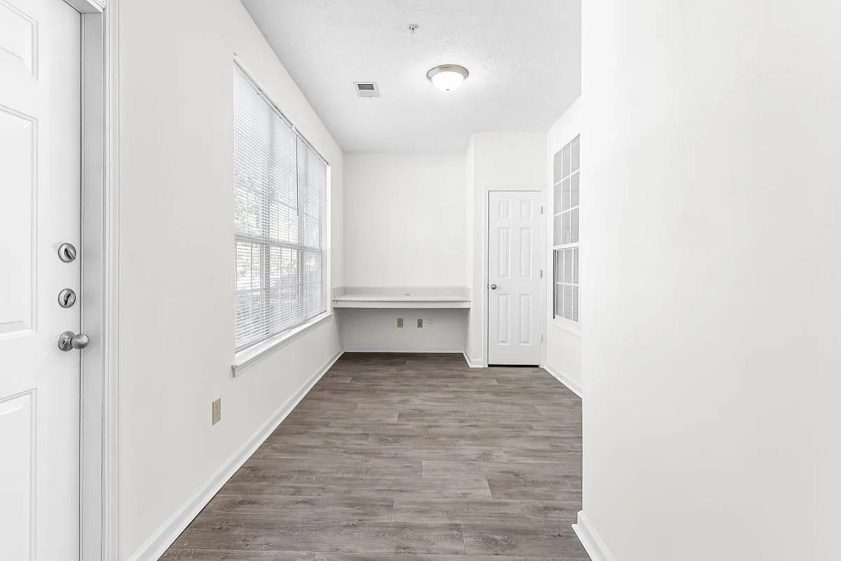 Bright entryway with large windows, sleek wood floors, and a convenient built-in desk, perfect for a home office  at Lake St James Apartments.