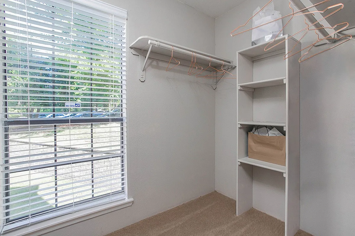 Bright and spacious walk-in closet at Autumn Ridge Apartments with built-in shelving and ample natural light, offering a chic and organized storage solution.