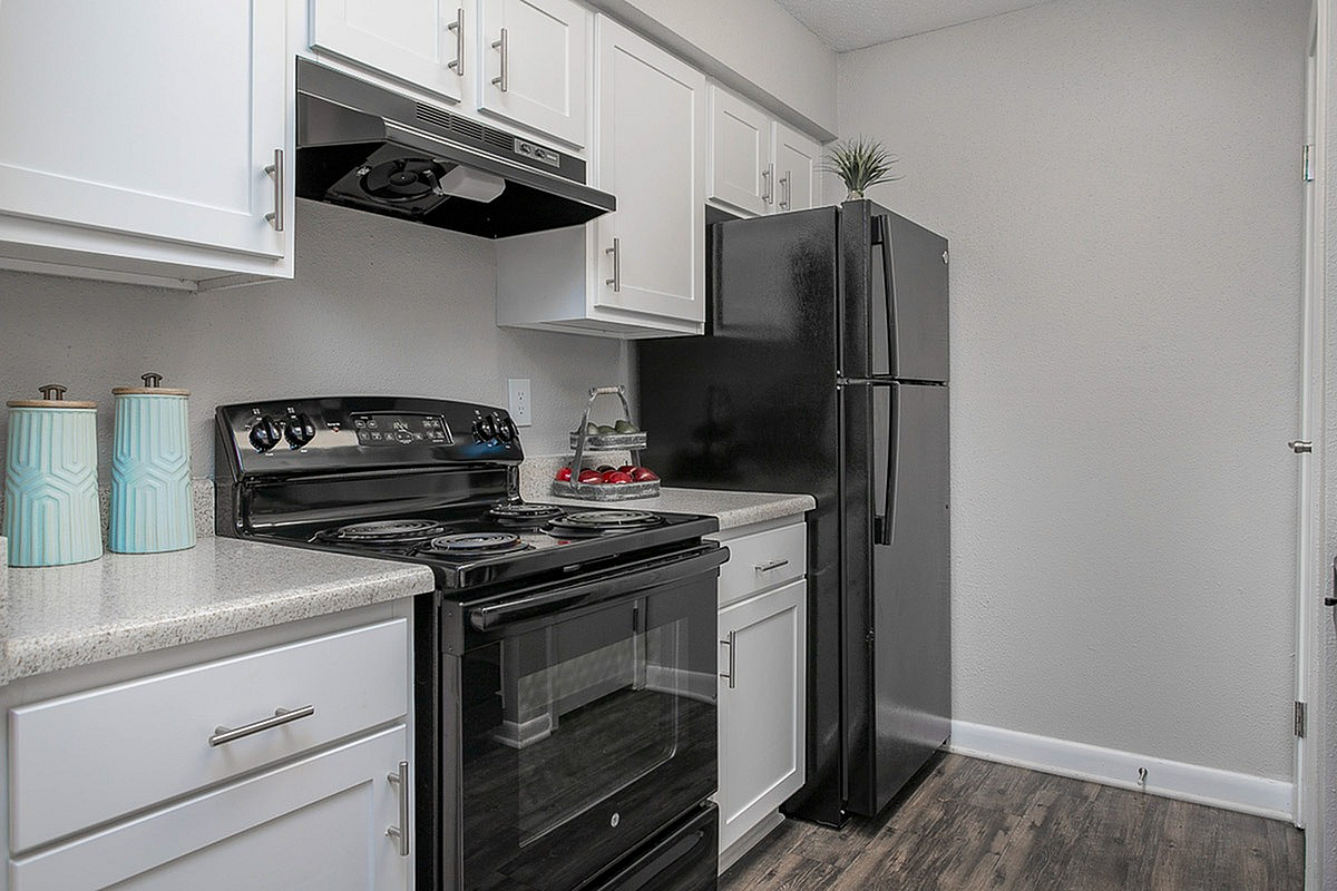 Modern kitchen at Autumn Ridge Apartments with sleek black appliances, spacious countertops, and chic white cabinetry offering a stylish culinary space.