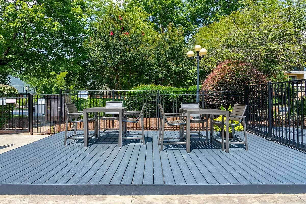 Charming outdoor patio at Autumn Ridge Apartments with modern seating, surrounded by lush greenery and vibrant trees, creating a serene and inviting atmosphere.