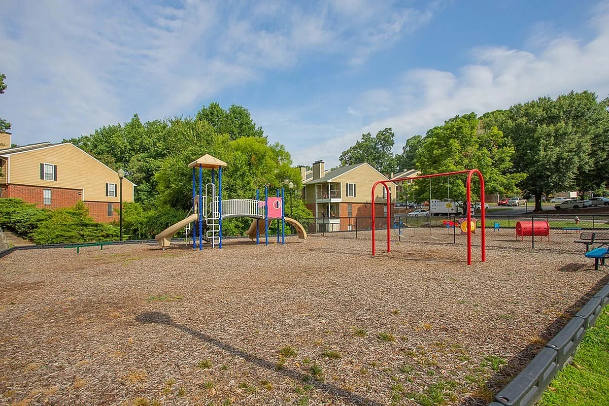 Inviting playground with vibrant slides, swings, and lush greenery, perfect for family enjoyment at Autumn Ridge Apartments.