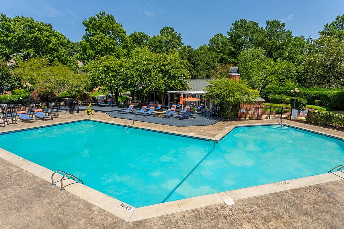 Inviting outdoor swimming pool at Autumn Ridge Apartments with stylish lounge chairs and lush greenery, perfect for relaxation and leisure.