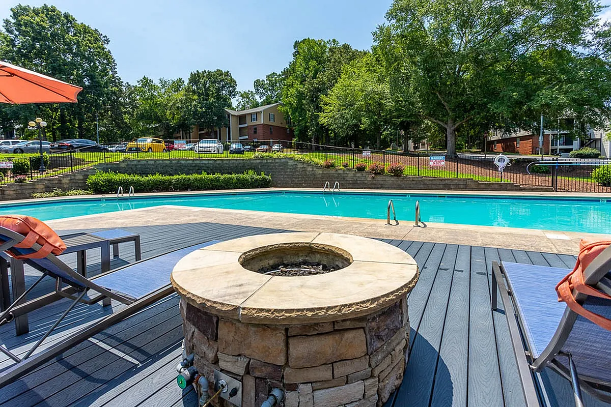 Inviting outdoor pool area at Autumn Ridge Apartments with stylish loungers and a cozy fire pit, perfect for relaxation and entertaining.