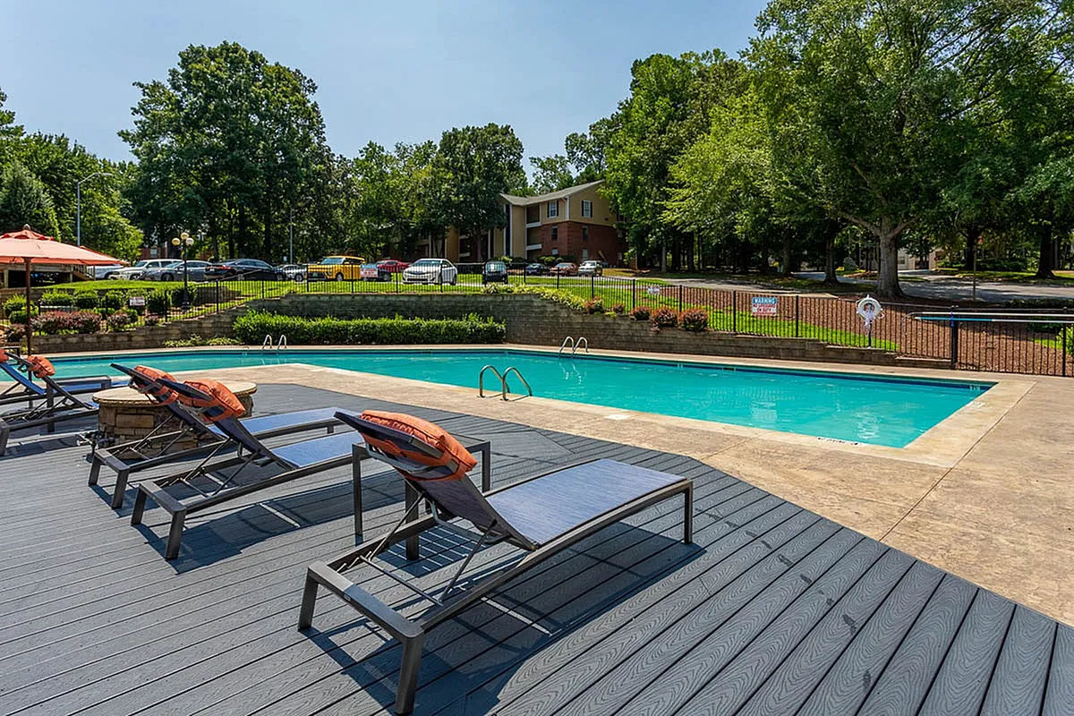 Inviting outdoor pool area at Autumn Ridge Apartments with modern lounge chairs surrounded by lush greenery, perfect for relaxation and leisure.