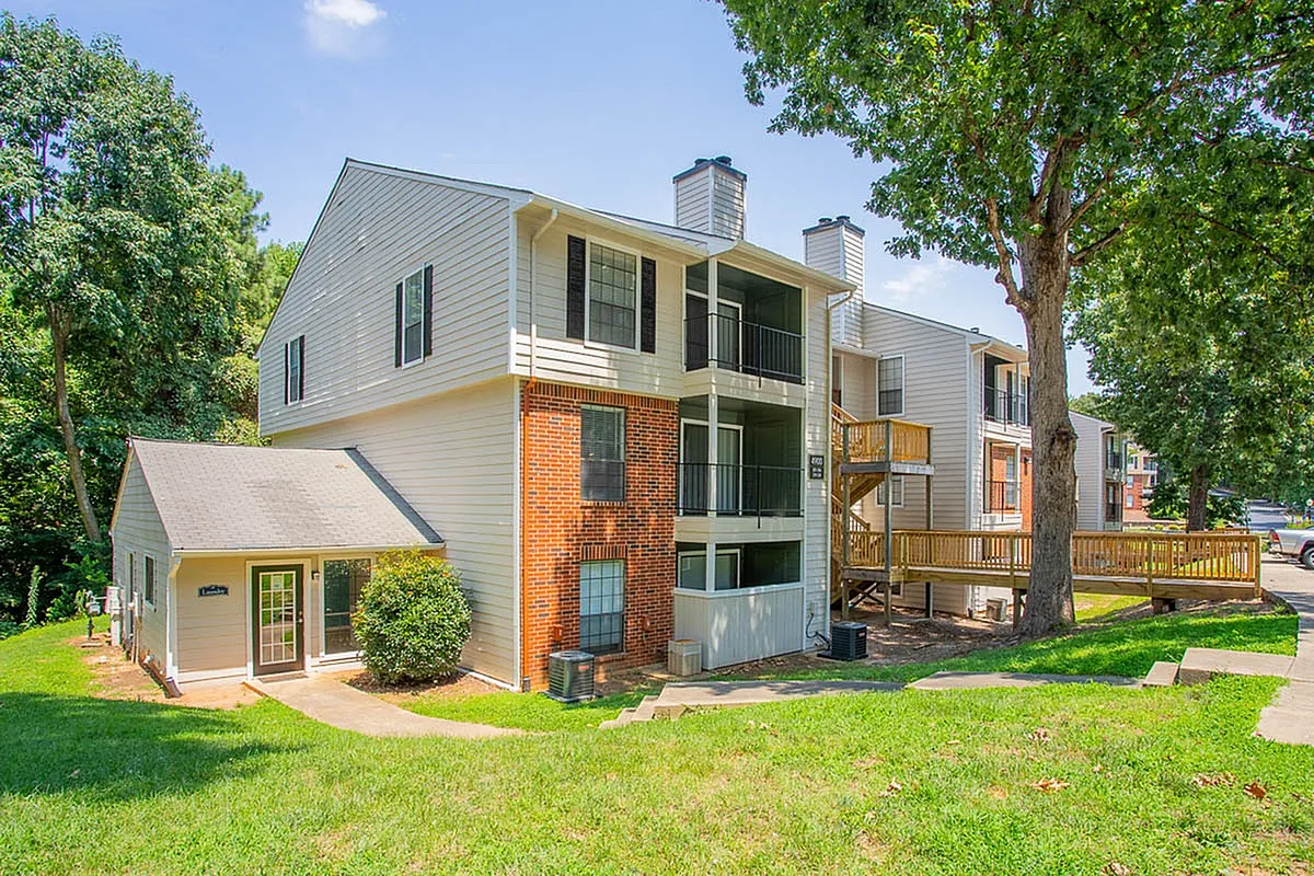 Charming three-story apartment complex, Autumn Ridge Apartments, with brick and siding exterior, nestled among lush greenery and featuring private balconies.