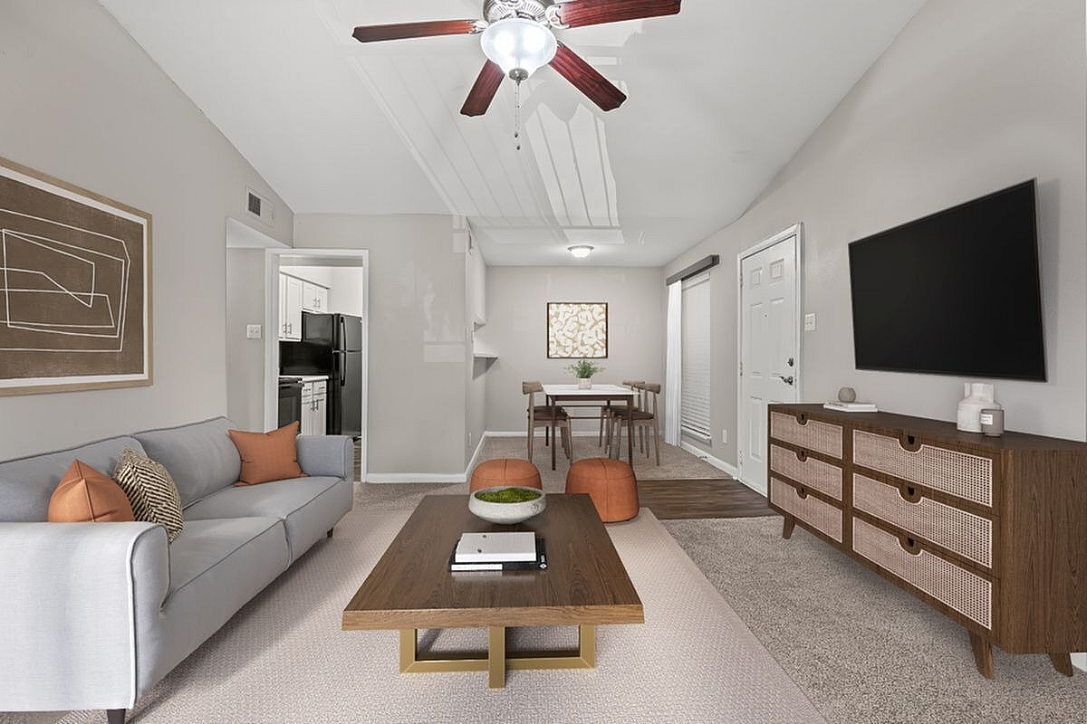 Modern living and dining area featuring a cozy gray sofa, elegant wooden coffee table, and sleek entertainment unit, flowing into a stylish dining space with contemporary chairs at Autumn Ridge Apartments