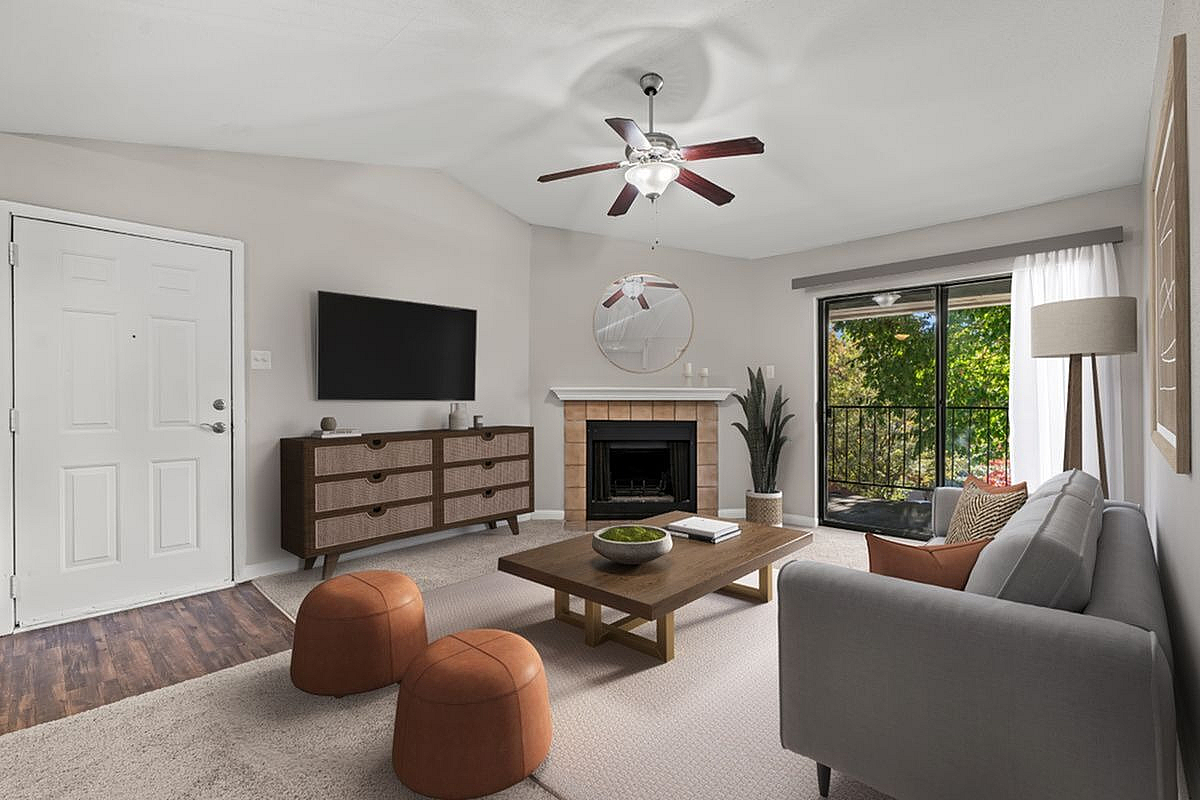 Inviting living room featuring modern decor, cozy fireplace, elegant ceiling fan, and a bright sliding door leading to a lush outdoor view at Autumn Ridge Apartments