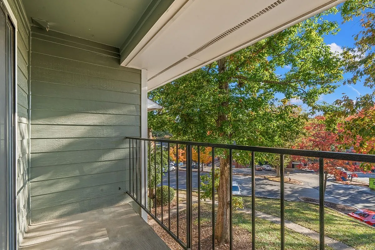 Charming balcony view with serene green surroundings and vibrant autumn foliage at Autumn Ridge Apartments.