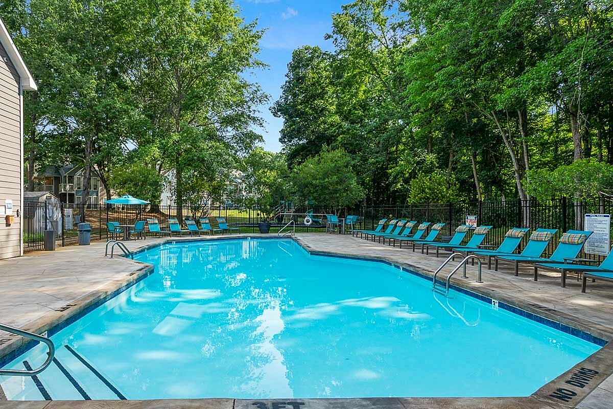 Inviting outdoor swimming pool surrounded by lush greenery and modern lounge chairs, perfect for relaxation and leisure at Park at Oak Ridge Apartments.