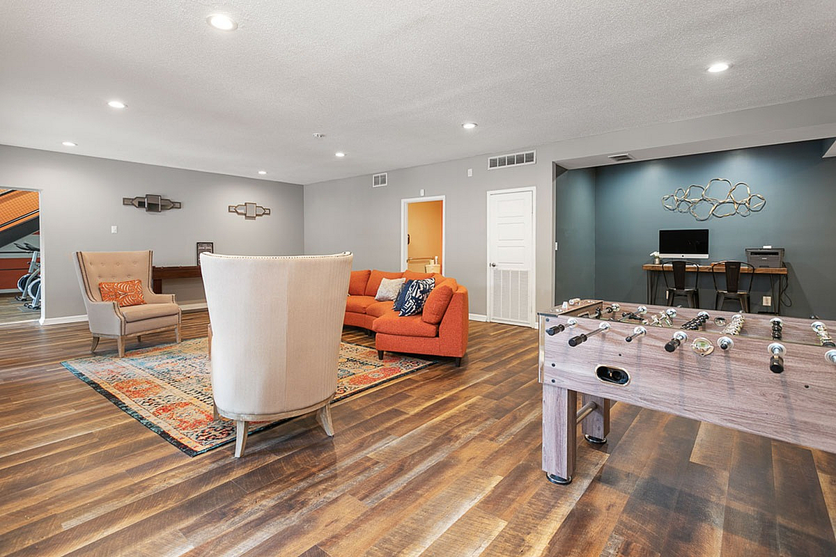 Stylish clubroom at Park at Oak Ridge Apartments with an inviting open-concept living area, featuring cozy seating, vibrant decor, and a fun foosball table.