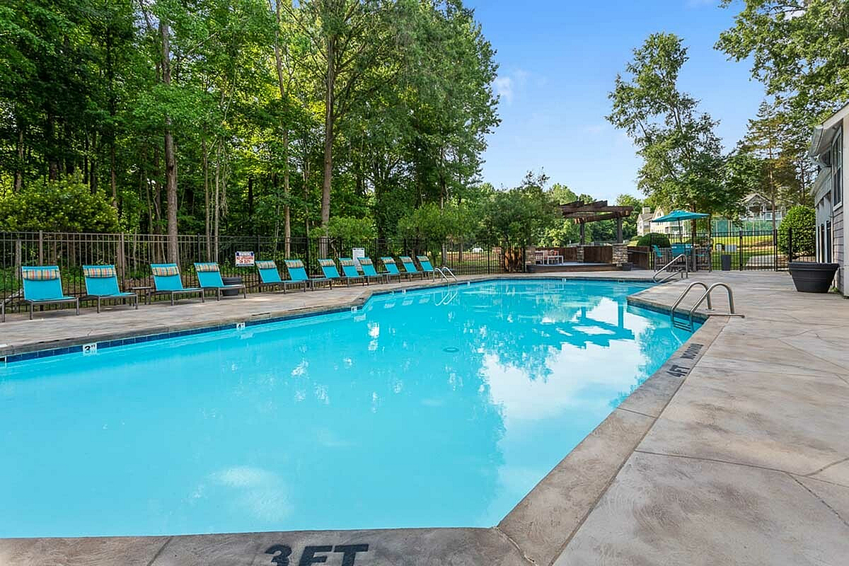 Inviting outdoor pool at Park at Oak Ridge Apartments surrounded by lush greenery, with comfortable loungers and a relaxing ambiance.
