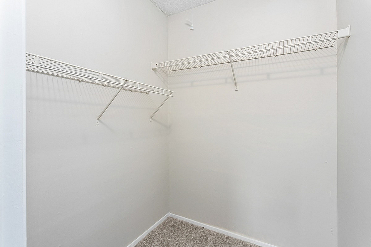 Spacious walk-in closet at Park at Oak Ridge Apartments with pristine white walls and ample shelving, offering abundant storage space.