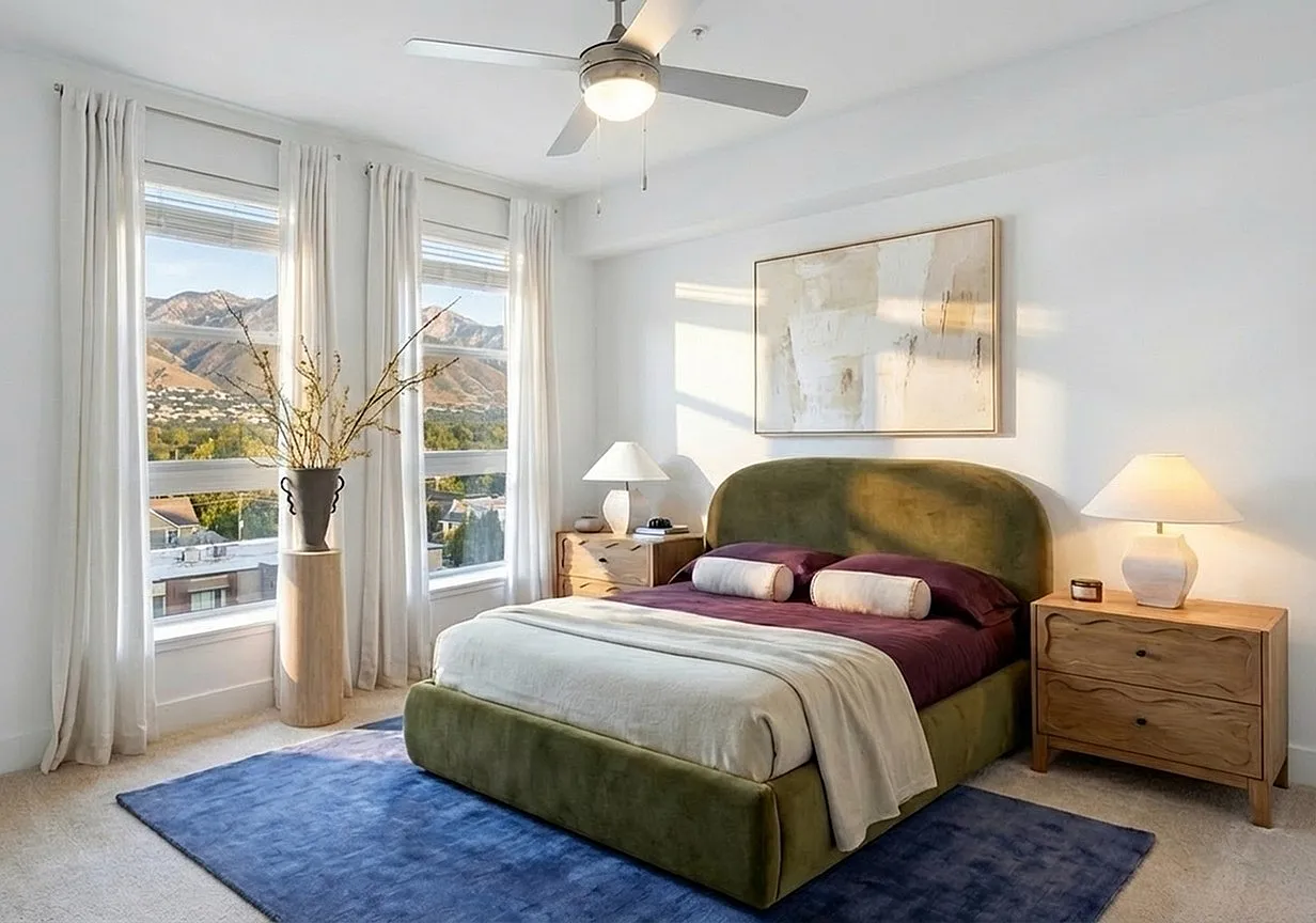 Elegant bedroom with mountain views, featuring a plush green bed, modern art, and warm natural light at The Richmond Apartments in Salt Lake City.