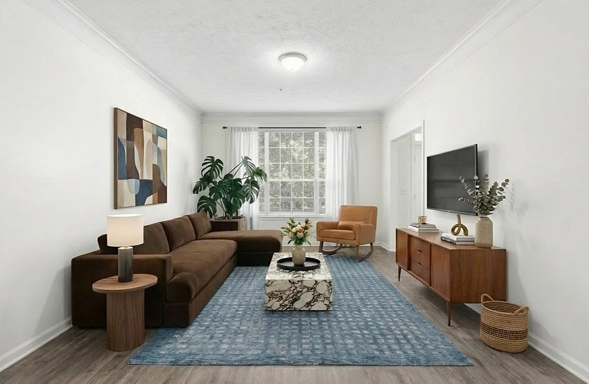 Inviting living room with a plush brown sectional, elegant decor, and natural light streaming through large windows, perfect for relaxation and entertainment at Lake St James Apartments in Conyers GA